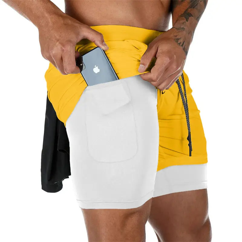 Men 2 in 1 gym shorts quick dry workout activewear featuring yellow and white two-tone fabric with a side pocket holding a smartphone.