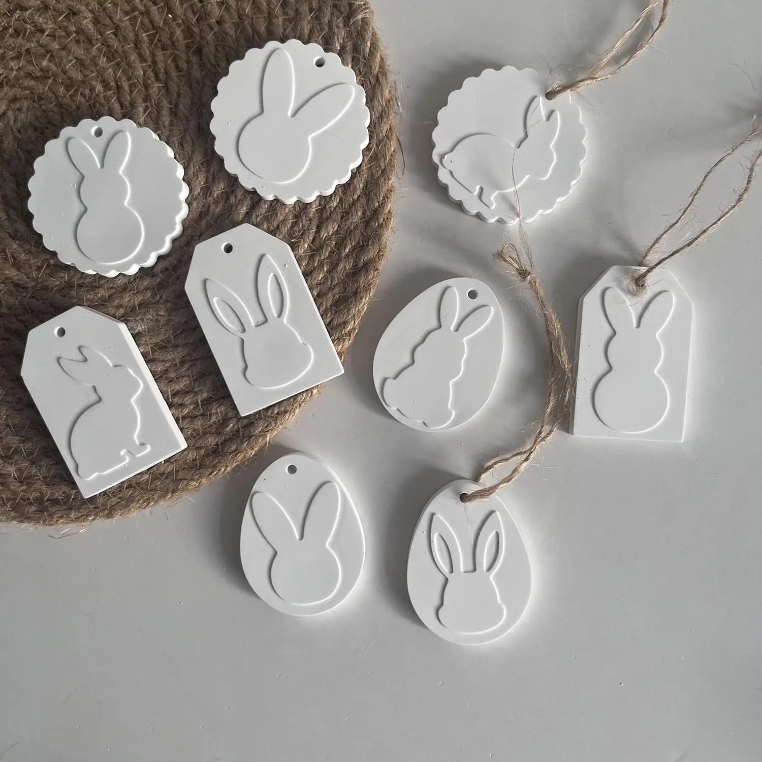 white bunny-shaped decorative tags made from silicone resin in various shapes and sizes with some featuring attached twine for hanging from the easter bunny silicone resin pendant mold