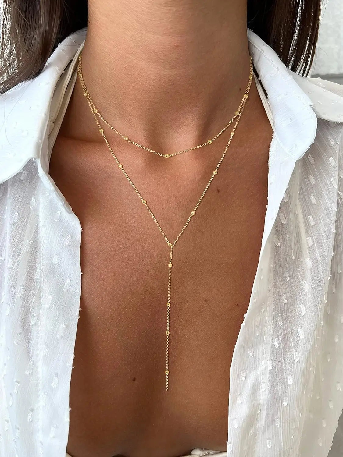 Collier en « y » à superpositions en or pour femmes, présentant une chaîne délicate à tonalité dorée avec de petites perles sphériques.