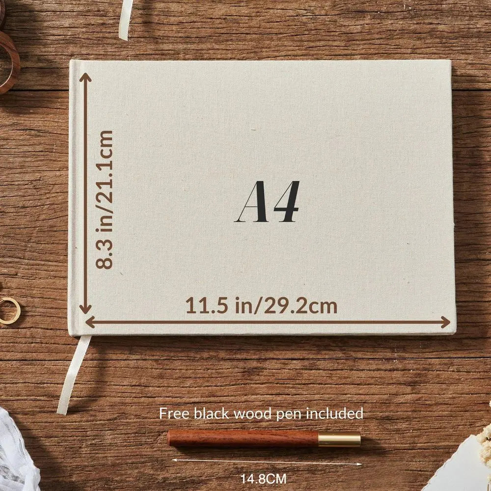 A cream-colored linen custom wedding guest book and pen linen photo album with textured fabric binding black printed dimensions and a white ribbon bookmark.