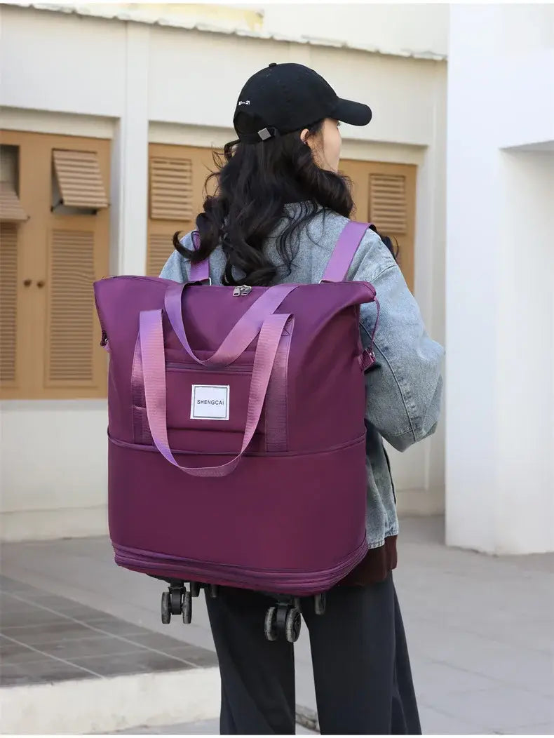 Un sac duffel roulant violet à grande capacité, avec des sangles assorties, et une petite étiquette blanche à l’avant pour un usage en voyage.