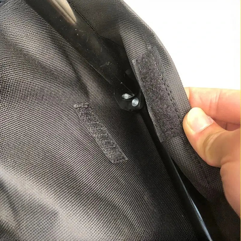 Black fabric zipper pull with metallic slider and two adhesive strips for secure attachment on the foldable pet cot metal frame model number 1.