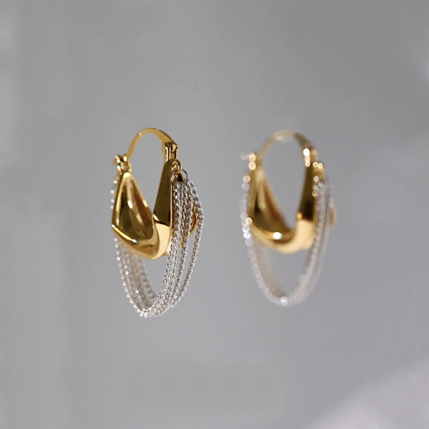 Kettenquasten-Ohrhänger gold silber zweifarbig, mit zweifarbigen Gold- und Silber-Creolen im modernen, geschichteten Design und herabhängenden Ketten.