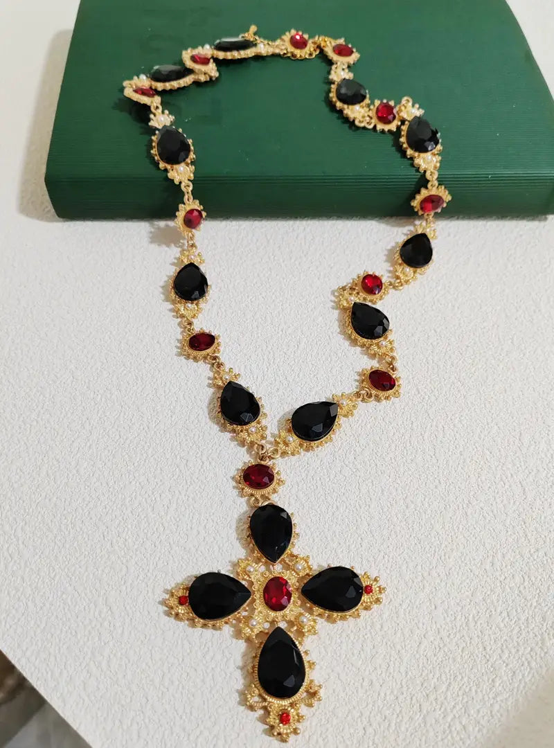 Collier ras du cou à déclaration en cristal à finition dorée, orné d’un pendentif en forme de croix, agrémenté de pierres noires en forme de larme et de pierres rondes rouges, pour des bijoux de soirée.