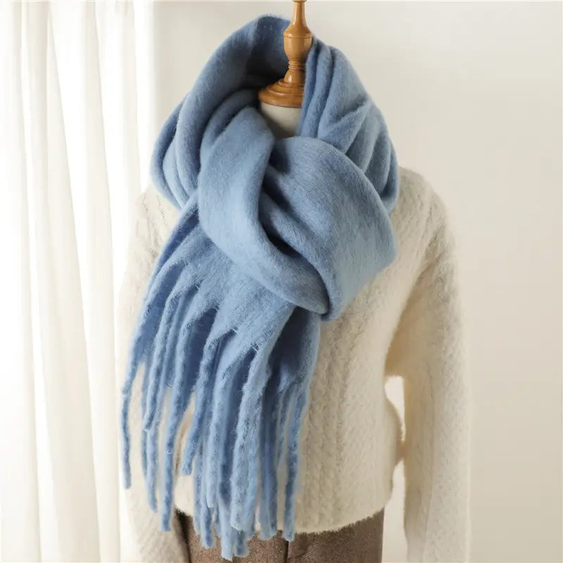 Ein weicher hellblauer Cashmere-ähnlicher Winterschal aus Wolle mit gefransten Kanten, drapiert um eine Schaufensterpuppe.