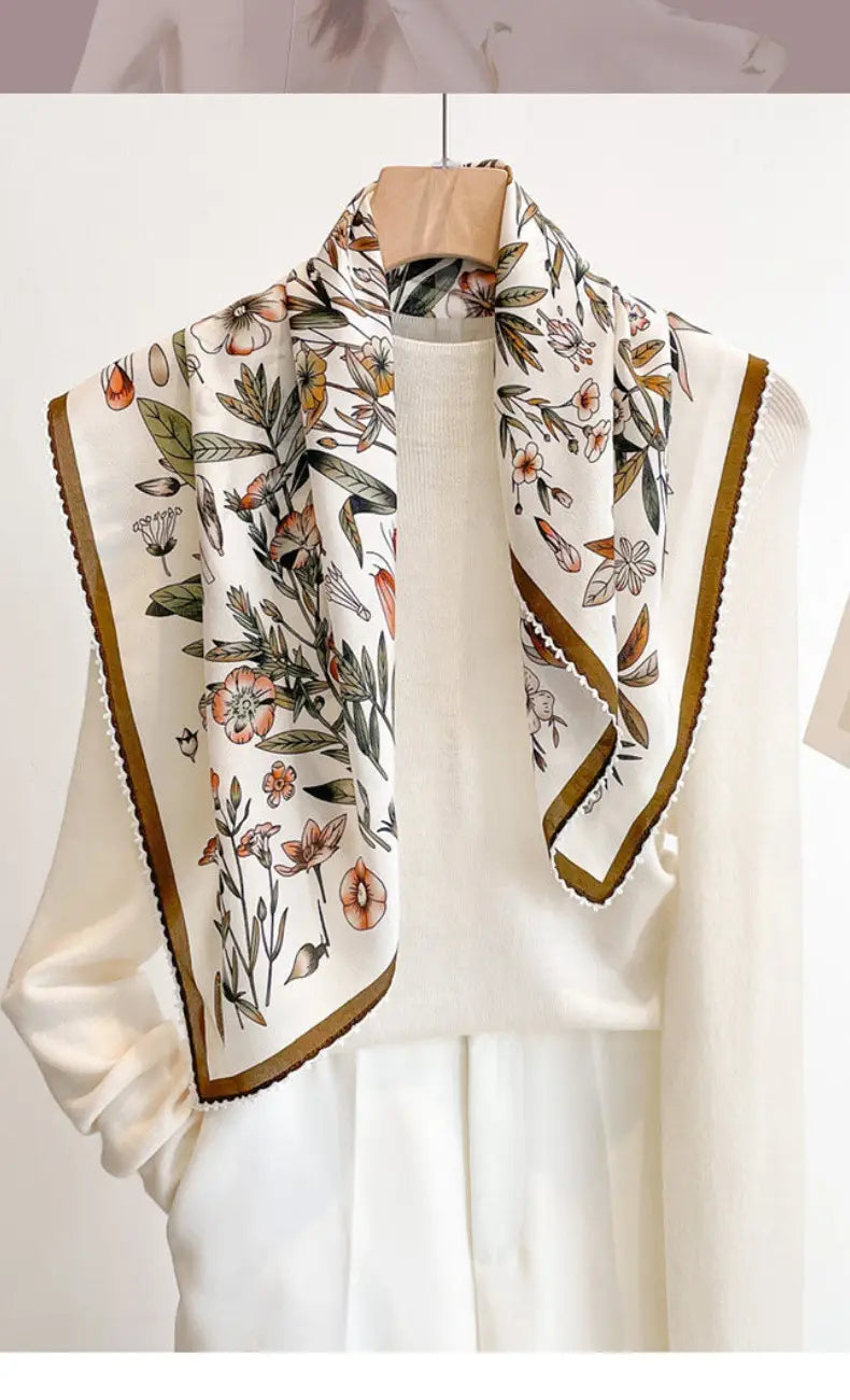 Silk floral square scarf featuring a delicate ivory silk fabric with a botanical print of pink and green flowers and mustard-yellow bordures.