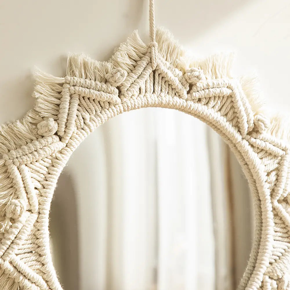 Cream-colored boho macrame wall mirror with intricate woven patterns and fringed edges ideal for living room home decor.