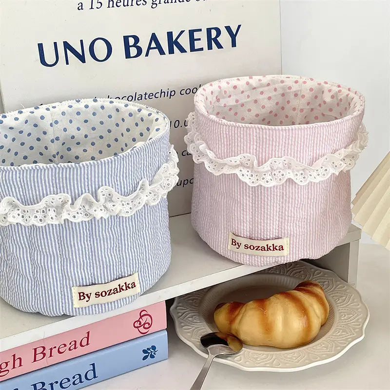 Gepolsterte Aufbewahrungskörbe für das Kinderzimmer: Pastellblau- und -rosage-streiftes Stoffdesign mit weißem Spitzenbesatz zur dekorativen und funktionalen Organisation.
