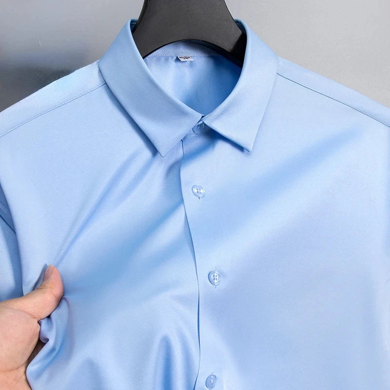 Chemise habillée bleu clair pour homme à coupe slim, en coton rigide à boutons, avec col classique et détails de surpiqûre discrets, conçue pour être portée avec des manches longues anti-froissement.