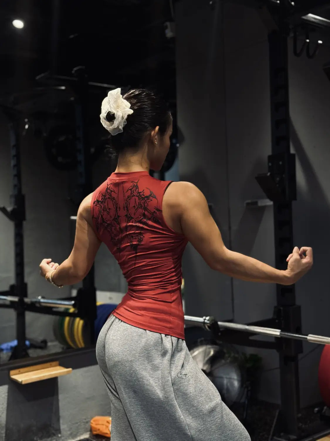 Camiseta sin mangas gótica de fitness de secado rápido roja, con material de secado rápido y un diseño negro intrincado en la espalda, mostrado desde el lado posterior.