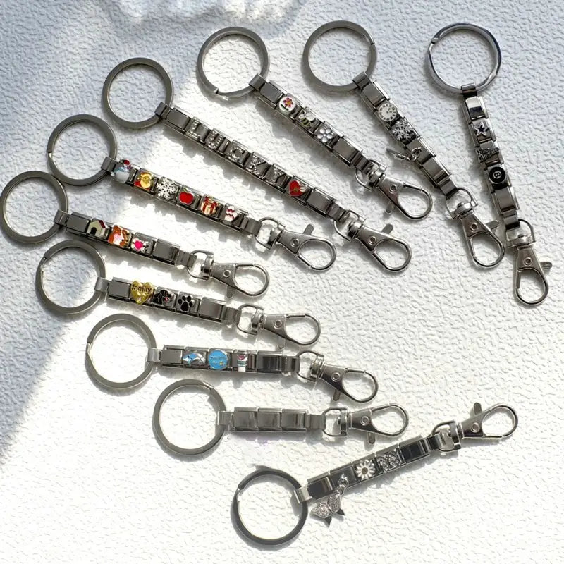 Una colección de llaveros con dije de eslabones italianos con acabado plateado, con eslabones metálicos entrelazados, dijes esmaltados de colores y elementos decorativos para uso personalizado en bricolaje.