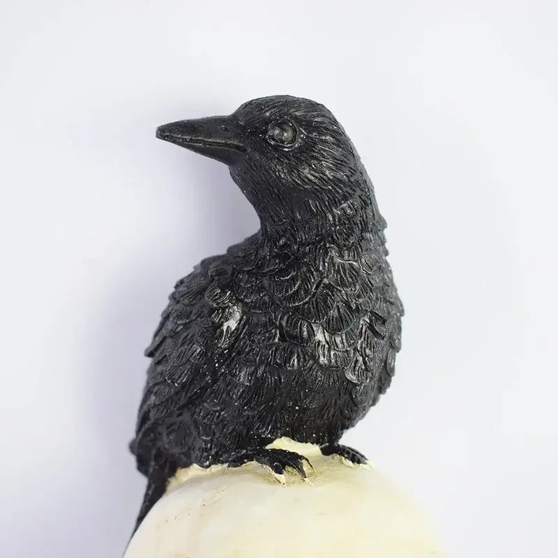 Figura de cuervo negro con textura de plumas detallada posada sobre una base color crema como parte de la lámpara de jardín solar de cráneo y cuervo.