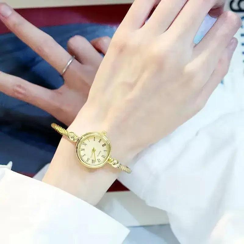 Women stainless steel quartz bangle watch featuring a gold-toned rope-style bracelet with a round face and roman numeral markings.