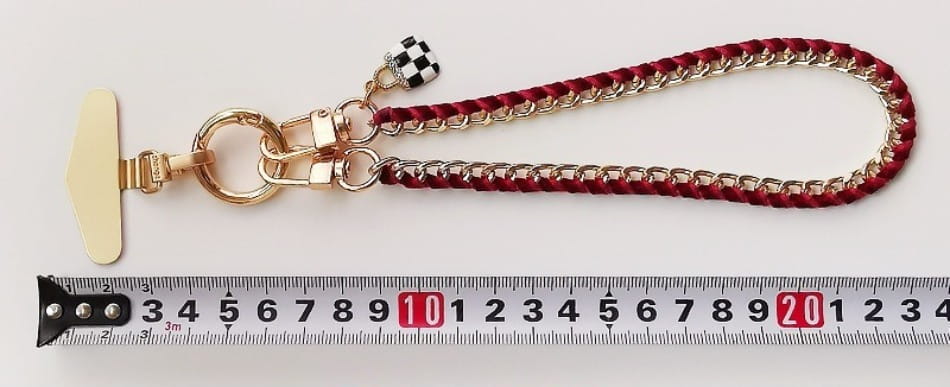 Roter und goldfarbener geflochtener Ketten-Handy-Handgelenkriemen mit einem karierten Flaggenanhänger, entworfen als Anti-Lost-Handylanyard.