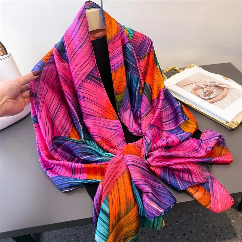Seidenschal für Damen im Colorblock-Stil als Frühlingsschal-Wickel, mit einem lebendigen mehrfarbigen Design und kräftigen diagonalen Streifen in Pink, Orange, Lila und Petrol, elegant drapiert über einer Schaufensterpuppe.