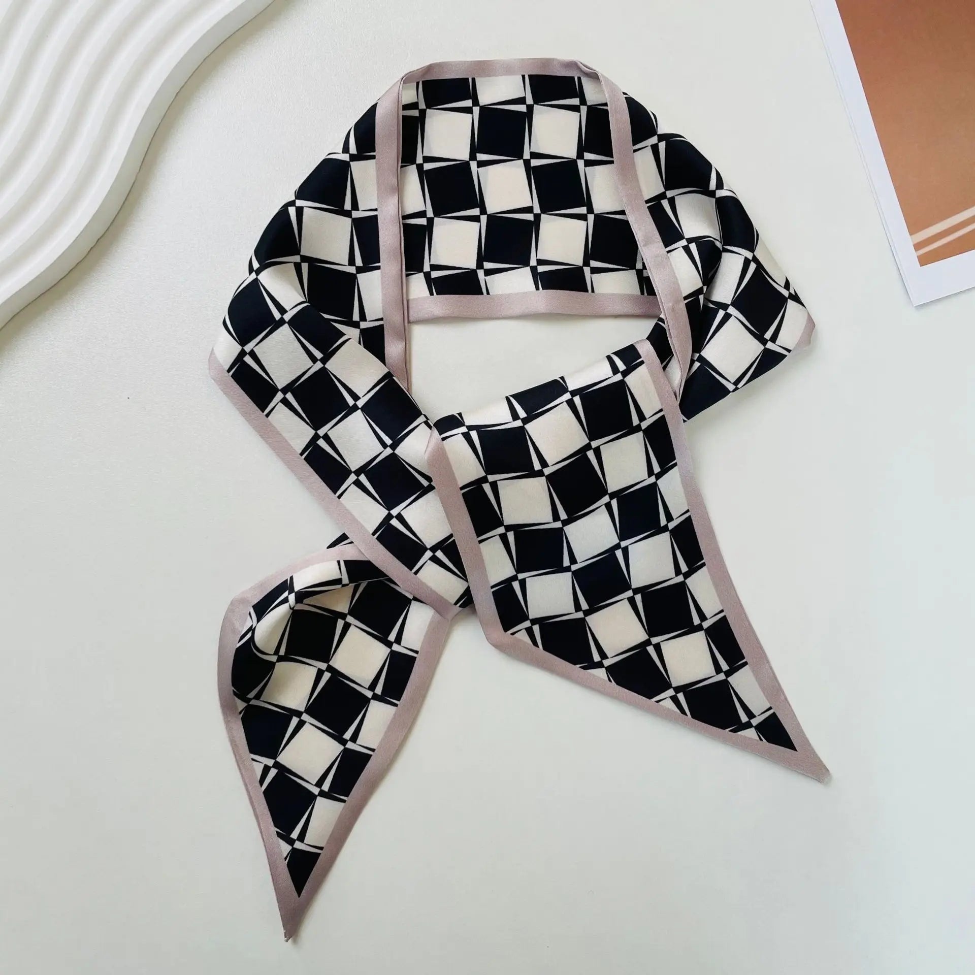 Pañuelo de seda elegante en negro y blanco con patrón geométrico, con un borde satinado color lavanda suave, diseñado como una banda de escote cuadrado.