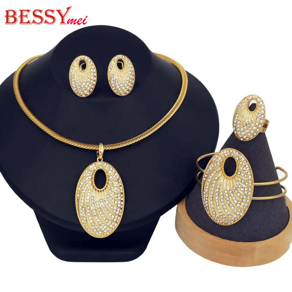 El conjunto de joyería de novia chapada en oro incluye un collar, aretes y una pulsera en tono dorado adornados con pedrería brillante en un diseño ovalado.