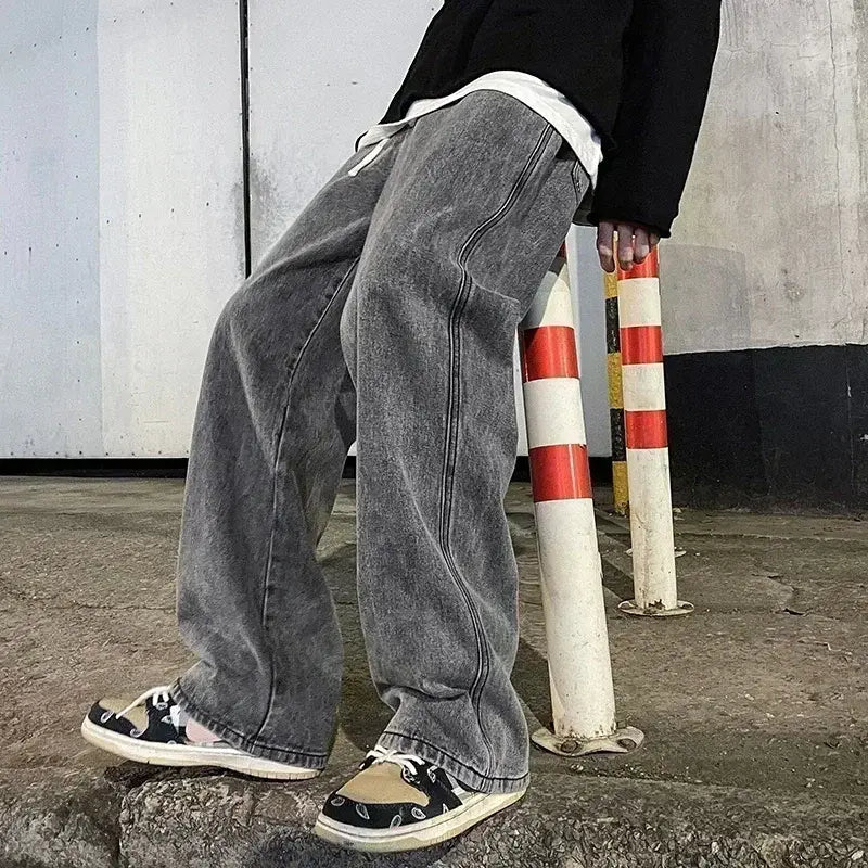 Jeans en denim gris à jambes larges pour hommes, avec un délavage délavé et des surpiqûres visibles, conçus pour un style streetwear coréen ample.