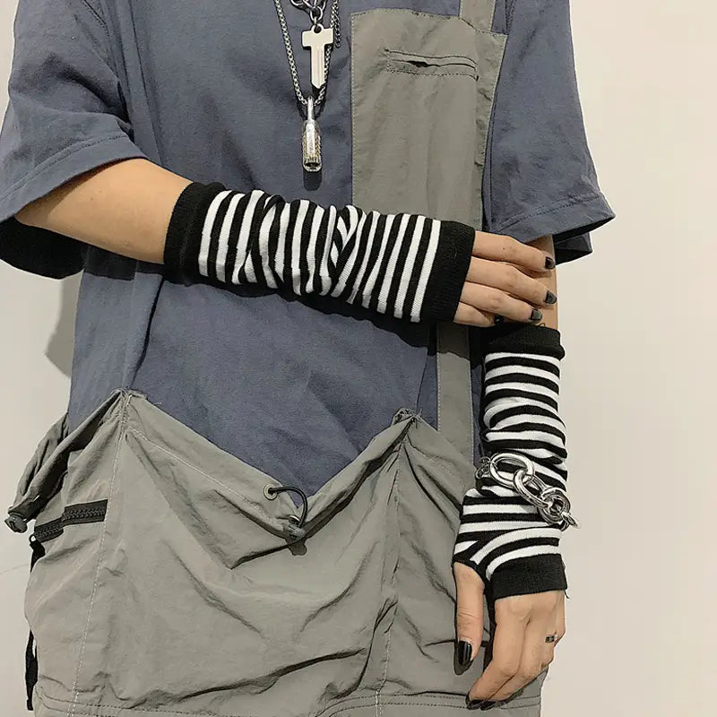 Striped knit fingerless arm warmers in black and white with knit fabric and a chunky silver chain detail at the wrist.