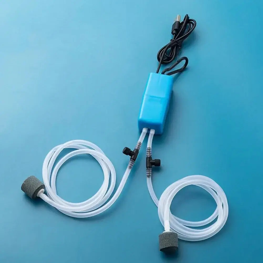 黒い電源コードと透明なチューブを備えたブルーのプラスチック製静音USB水槽用エアポンプで、グレーの多孔質ディフューザーに接続し、酸素ポンプとしての水槽エア運用に使用します。