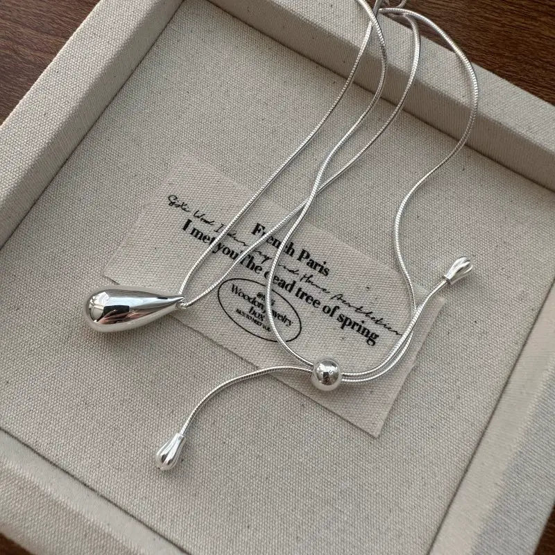 Collier goutte de larmes en argent sterling avec un pendentif goutte de larmes épuré et poli sur une délicate pièce de joaillerie en chaîne serpent.