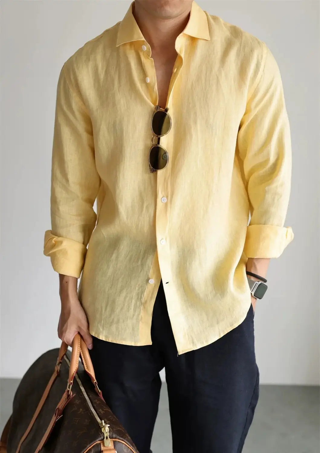 A pale yellow men cotton linen casual button down shirt with long sleeves rolled cuffs and a button front.
