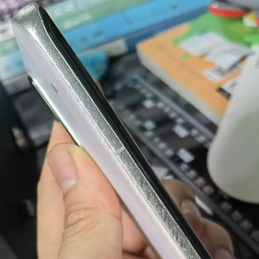 Teléfono móvil plateado con marco y borde metálico elegante, con bisel negro de la pantalla, mostrado como parte de una máquina de laminación al vacío de película para teléfonos móviles para reducir el costo de envío y mejorar la protección del dispositivo.