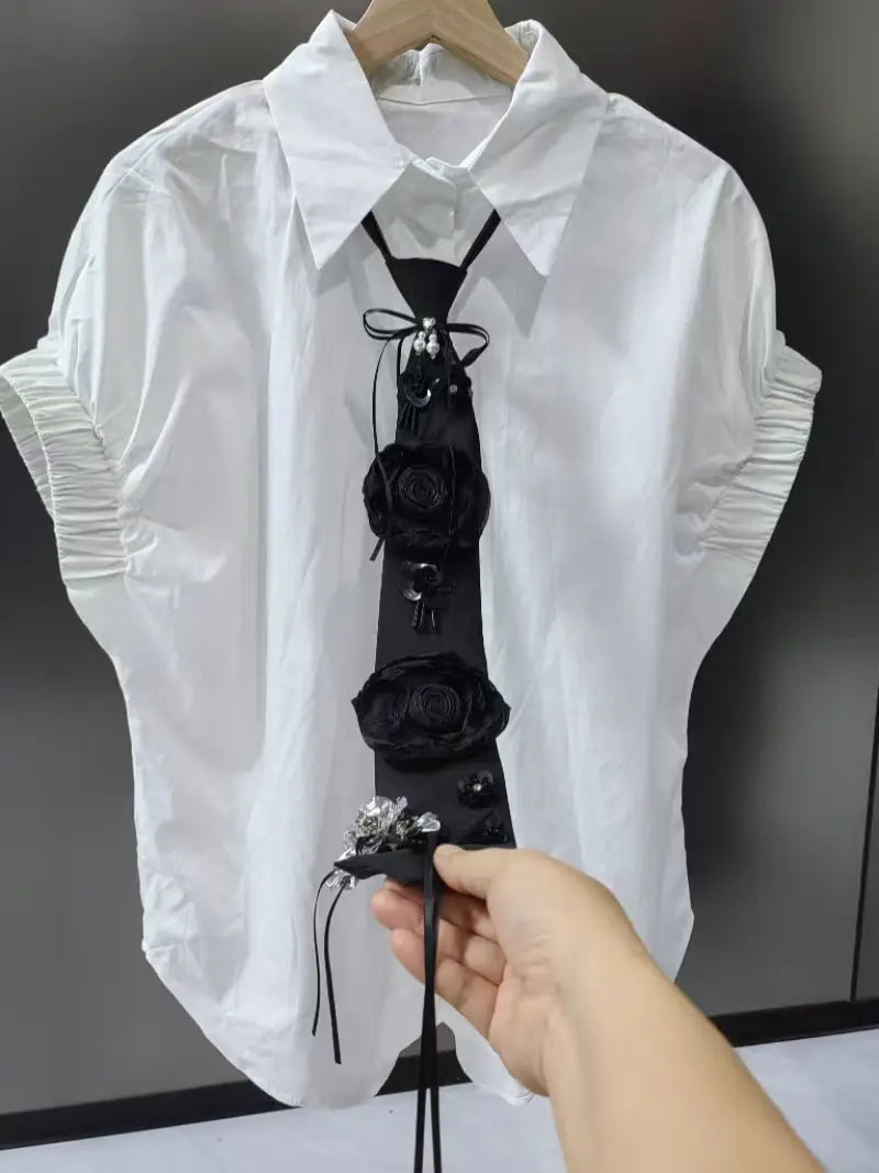 short sleeve shirts blouses for women featuring a black floral tie with fabric roses and metallic embellishments.