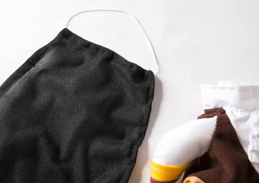Schwarze Netzgesichtsmaske mit weißem elastischem Trageriemen als Teil eines Piratenhundekostüms mit Hut