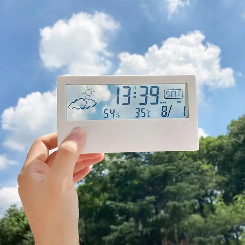 white rectangular digital weather desktop alarm clock displaying time date temperature humidity and cloud sun icons