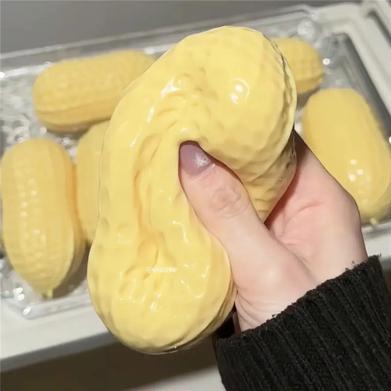 Un jouet sensoriel de type balle anti-stress en forme d’arachide, jaune brillant, avec une surface texturée, conçu pour un usage tactile sensoriel.