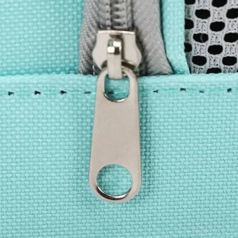 Tirette de fermeture éclair argentée élégante, de forme rectangulaire arrondie, avec ouverture circulaire, sur le tissu texturé vert menthe du sac bandoulière de transport pour animaux en maille respirante.