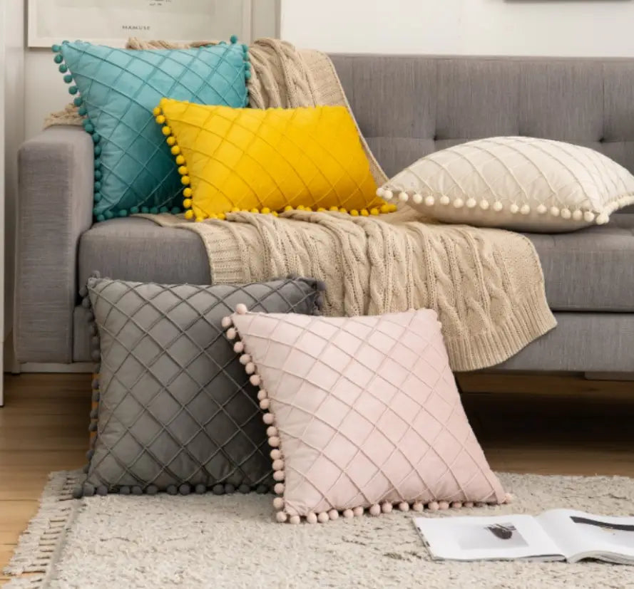 housse de coussin matelassée rose pastel avec garniture duveteuse à pompons, apportant une texture douce et des retours positifs en tant qu’option de housse de coussin décorative