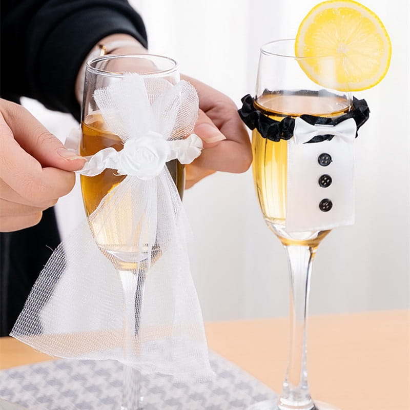 Juego de cubiertas de copas de vino para la novia y el novio con moño de tul blanco y corbata de satén negro que adorna las copas tipo champán.
