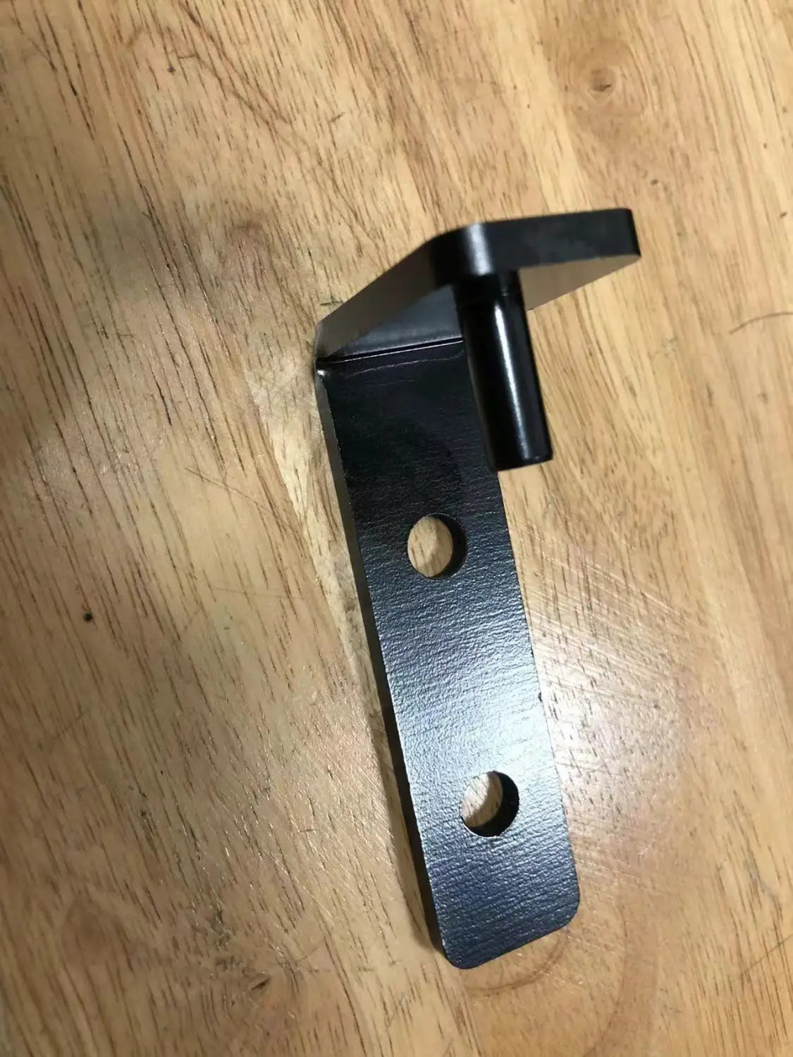 Heavy duty l shaped black metal shelf bracket with two circular holes and a protruding cylindrical piece designed to support up to 200kg.