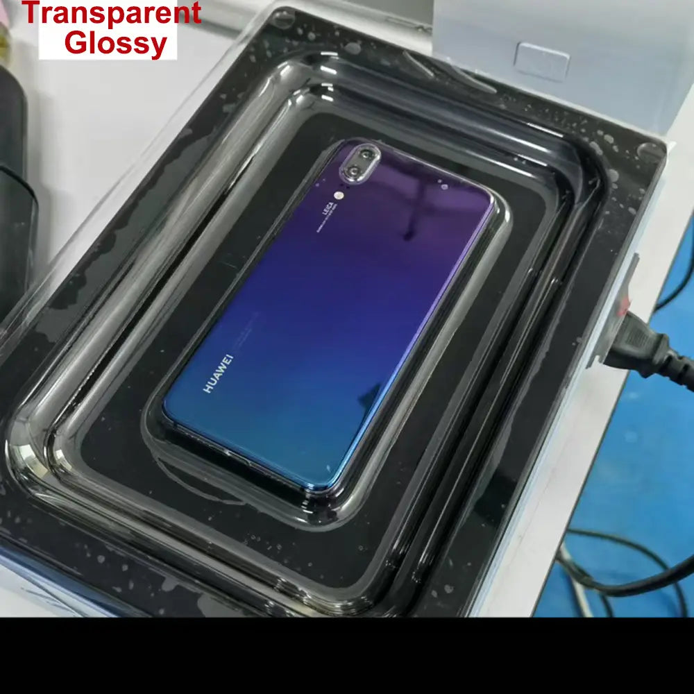 Un teléfono móvil Huawei con panel posterior degradado de azul a morado, protegido por una película transparente brillante, mostrado junto a una máquina de laminación al vacío de película para teléfonos móviles para reducir daños por costos de envío.