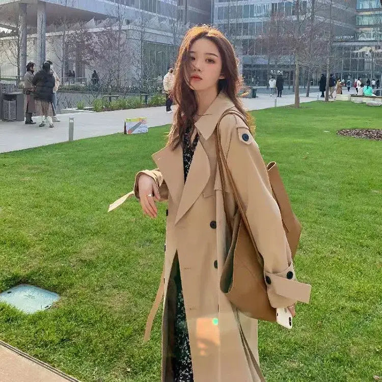 Beige women double-breasted trench coat with black buttons and belted waist designed as a casual windbreaker.
