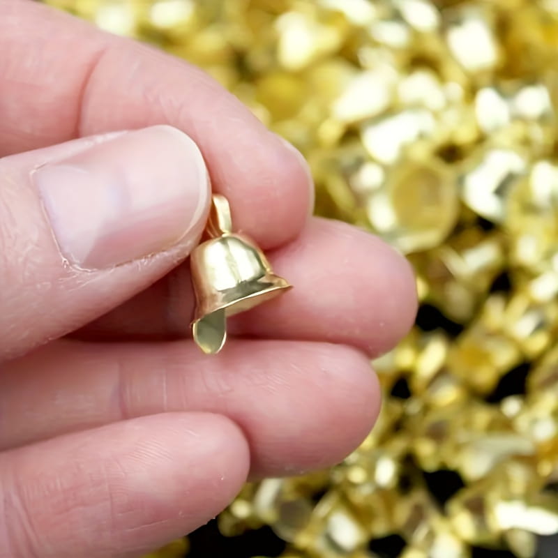 Une petite breloque de clochette de traîneau en métal doré, avec une finition métallique polie et une boucle au sommet pour l’attache, en lot de 20 pièces.