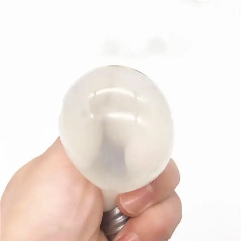 Juguete antiestrés tipo gomita con forma de bombilla de luz esférica blanca translúcida, con base metálica, diseñado para aliviar el estrés.