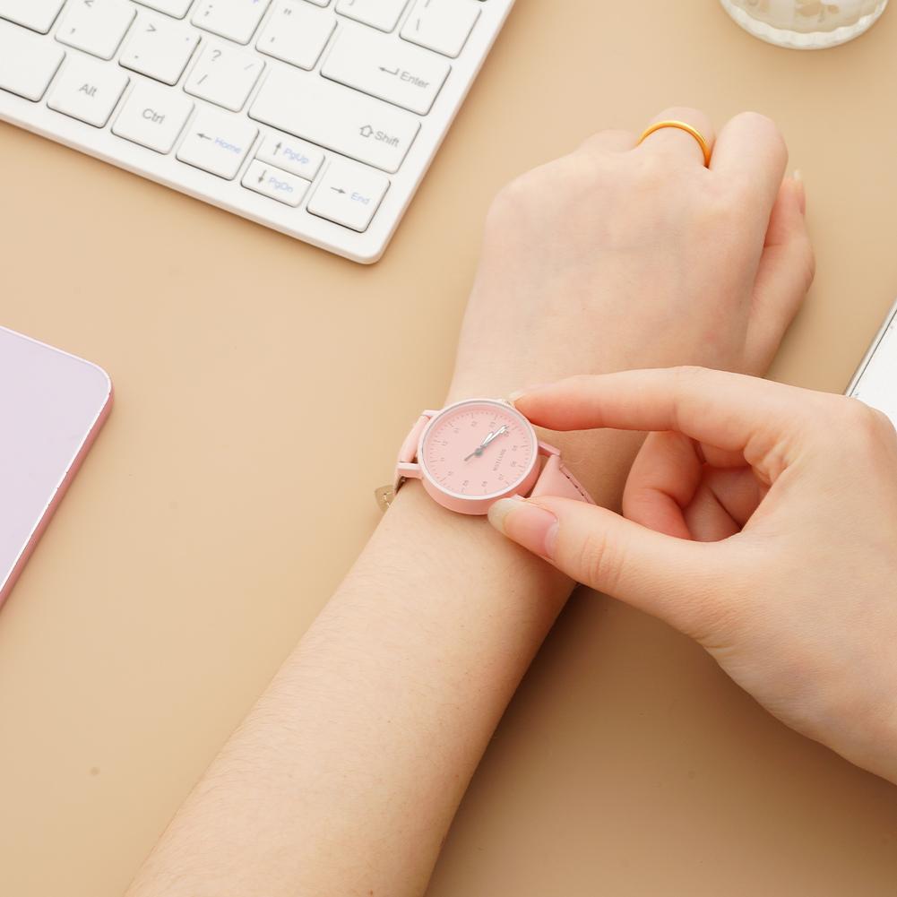 A delicate pink women quartz watch with a minimalist dial and slender hands, made of pu leather and waterproof, worn on a wrist.