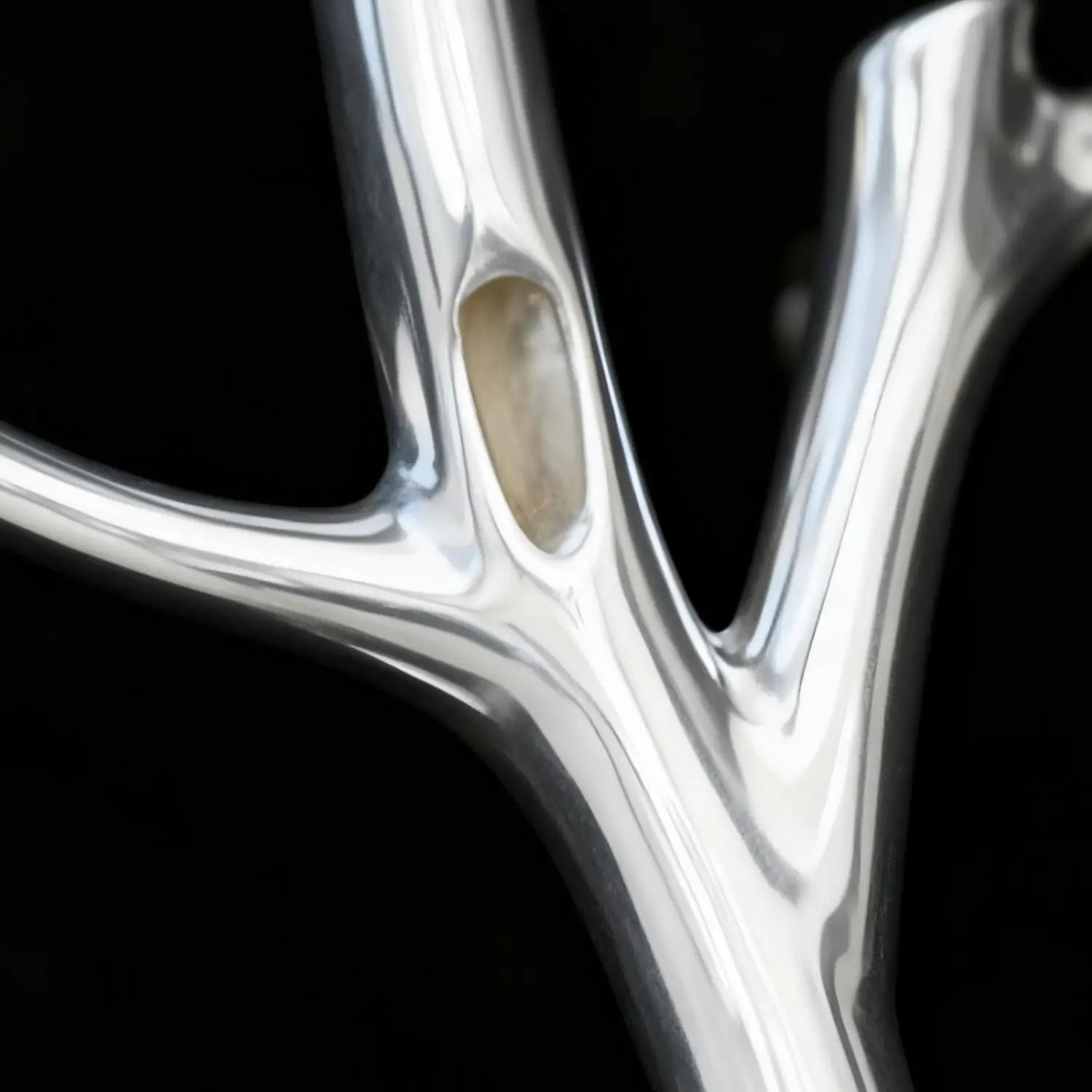 Silver tree branch brooch pin fashion corsage with a smooth reflective metallic surface and an embedded oval-shaped stone.