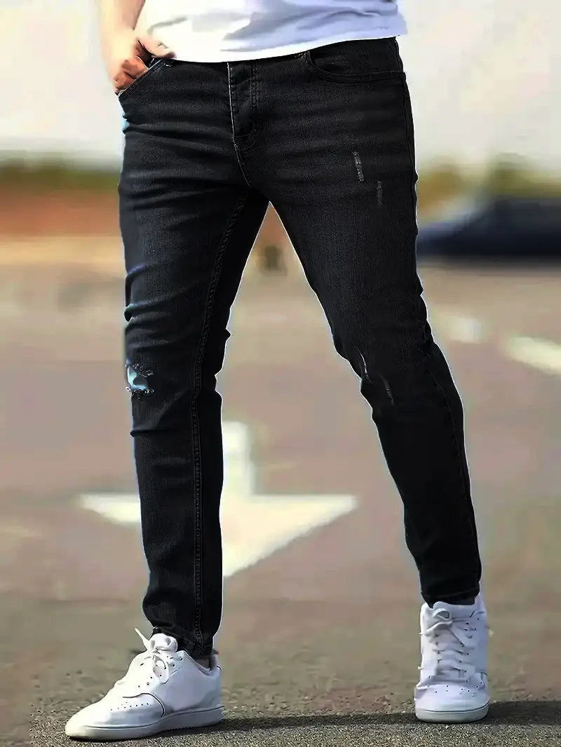 Men distressed skinny jeans in black denim featuring subtle fading and ripped details with a vintage slim fit design.