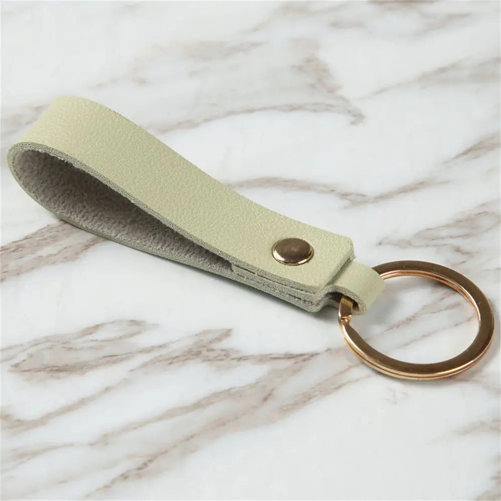 A minimalist pale green pu leather keychain with a gold-toned metal ring and button closure for stylish key organization.