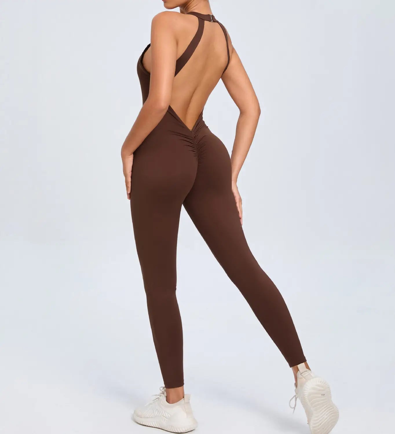 A sleek solid brown one-piece athletic jumpsuit with a halter neckline and an open back design shown from the back side for workout use.