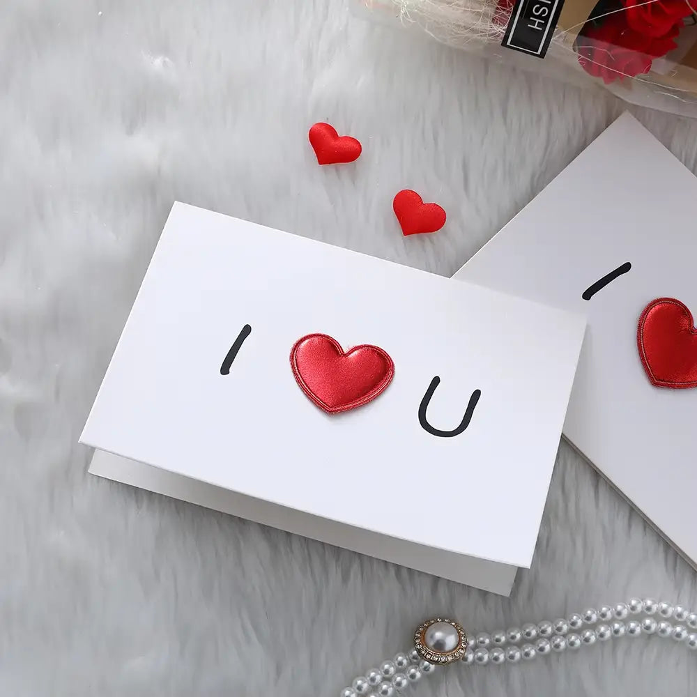 White valentine heart greeting card featuring a shiny red embroidered heart between black letters i and u designed for wedding invitations.