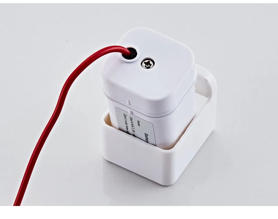 Weißer, quadratischer Bluetooth-Lautsprecher mit rotem Kabel und silberner Schraube auf der Oberseite, verwendet als Ersatzteil für den Batteriekasten eines Küchenarmaturensensors