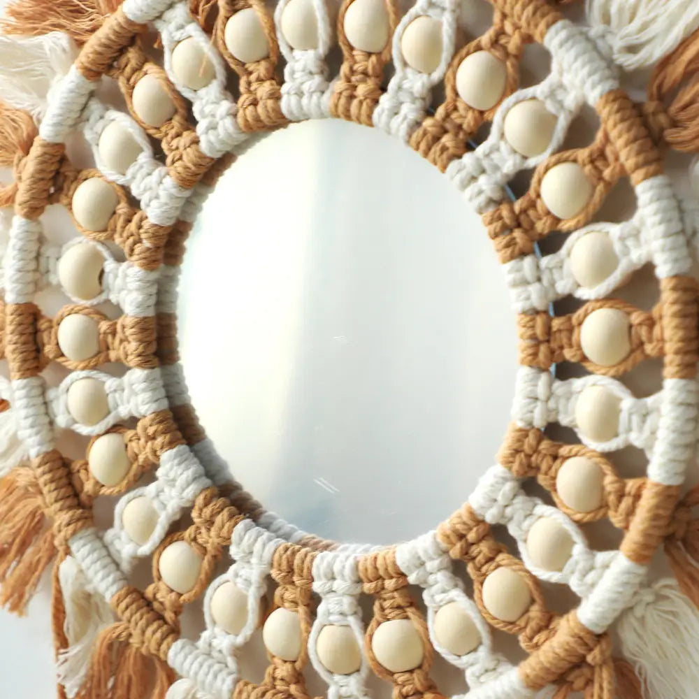 Boho macrame wall mirror with a circular beige and white cord frame, adorned with cream-colored wooden beads and tassels, designed for living room home decor.