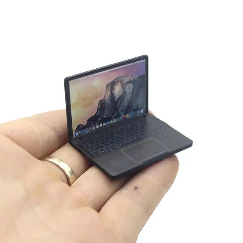 Schwarzer Miniaturlegierungs-Mini-Laptop mit glänzender Oberfläche und detaillierter Tastatur, in der Handfläche gehalten, zur Verwendung als Puppenhauszubehör