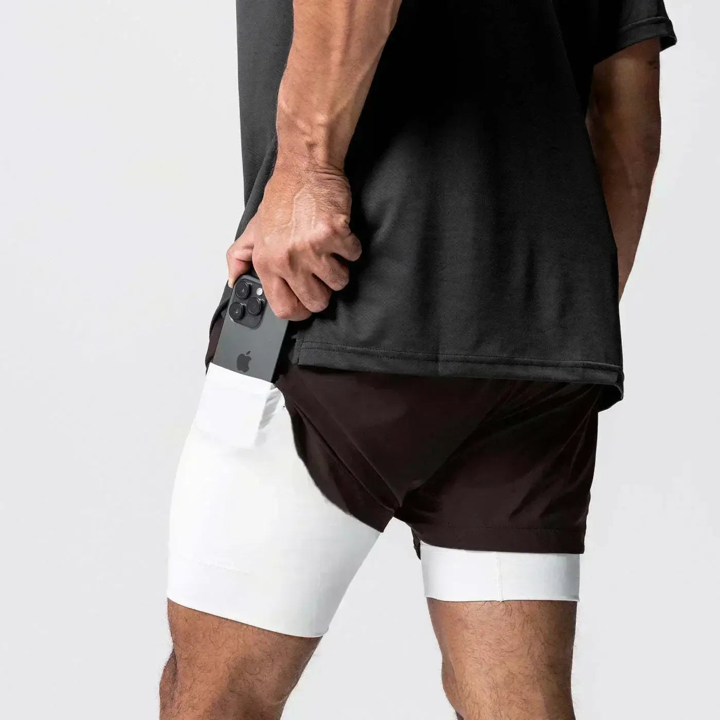 Hombres, pantalones cortos atléticos de dos capas negros y blancos para gimnasio con cintura elástica, bolsillo para teléfono integrado y trabilla para la toalla, para mayor comodidad en el entrenamiento.