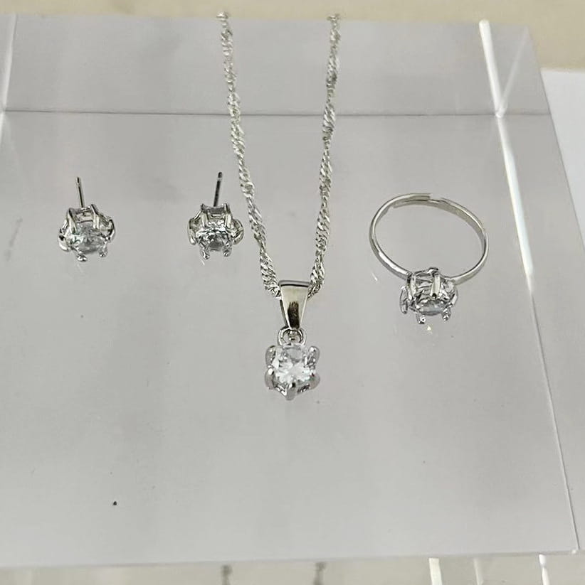 Juego de joyería de 5 piezas con circonitas cúbicas de color plateado, que presenta un collar de cadena trenzada con un dije de piedra transparente, aretes tipo botón a juego y un anillo ajustable tipo banda con un diseño clásico de solitario.